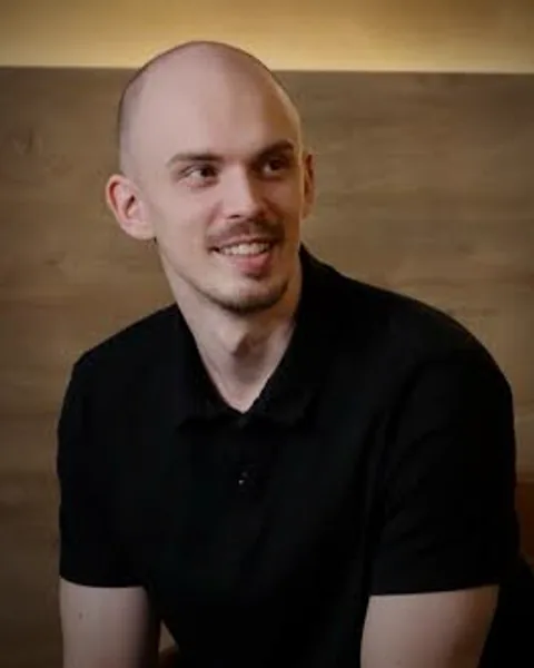 Mike im schwarzen Poloshirt vor einer Holzvertäfelung